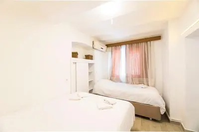 two beds in a small room with a window at Beautiful 2BR House w/AC 400meters Taksim Square in Istanbul