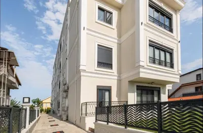 a white house with a black fence in front of it at Stylish 2BR and 3BR Izmit Apartments- Chic & Cozy in Çavuşçiftliği