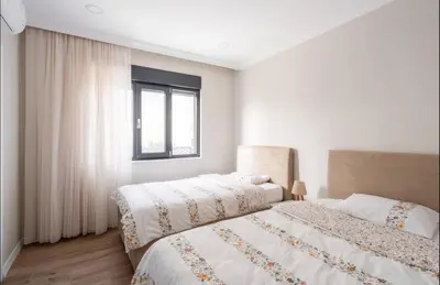 a white bedroom with two beds and a window at Stylish 2BR and 3BR Izmit Apartments- Chic & Cozy in Çavuşçiftliği