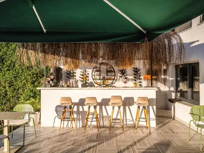 a bar with stools and a green umbrella at Hillora Hotel Buyukada in Adalar