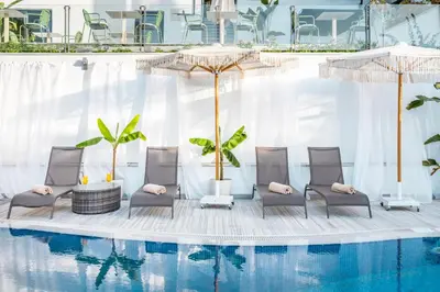 a pool with chairs and umbrellas in front of a building at Hillora Hotel Buyukada in Adalar