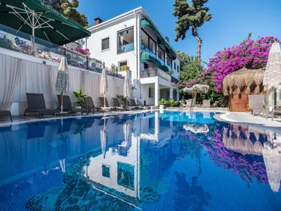 a swimming pool with chairs and umbrellas next to a building at Hillora Hotel Buyukada in Adalar