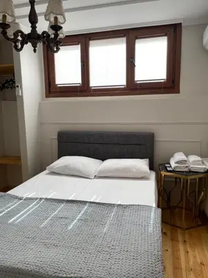 a bedroom with a bed with white sheets and two windows at Balat Tarihin içinden Pink Home 1 in Istanbul