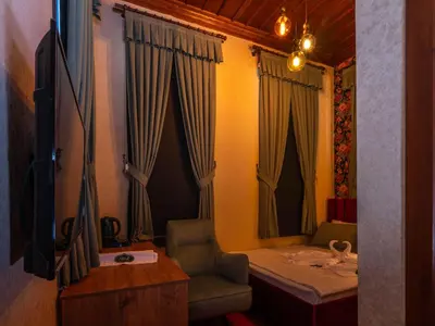 a room with a bed and a chair and curtains at Araz White House in Burgaz