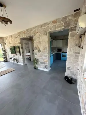 a large room with a stone wall and a kitchen at MEDASUİTE Stone House With Pool And Jacuzzi in Kandıra