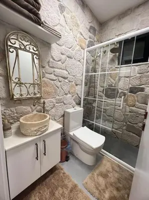 a bathroom with a white toilet and a stone wall at MEDASUİTE Stone House With Pool And Jacuzzi in Kandıra