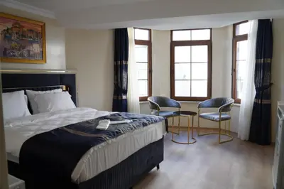 a bedroom with a bed and two chairs and windows at New Hotel Harbiye in Istanbul