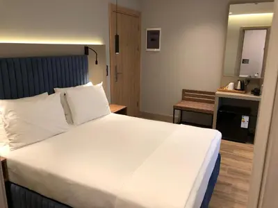 a bedroom with a large bed with white sheets at The Palm Bosphorus Hotel in Istanbul
