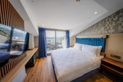 a bedroom with a large bed and a flat screen tv at The Palm Bosphorus Hotel in Istanbul