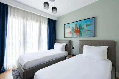 two beds in a hotel room with blue curtains at The Superior Living Kağıthane in Istanbul