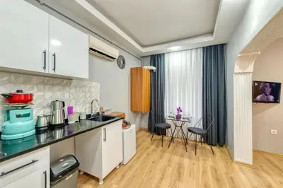 a kitchen with white cabinets and a table with chairs at Pio Apart Hotel in Istanbul