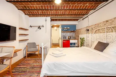 a bedroom with a white bed and a kitchen at Armel Homes Beyoğlu in Istanbul