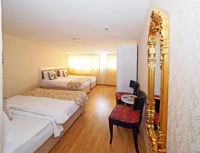 a room with two beds and a mirror and a chair at Nagehan Hotel Old City in Istanbul