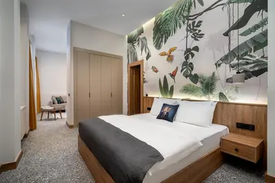 a bedroom with a large bed with a tropical wallpaper at Urban Quarters - Boğazkesen in Istanbul
