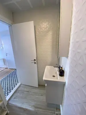 a white bathroom with a sink and a door at Sapphire Suites Taksim in Istanbul