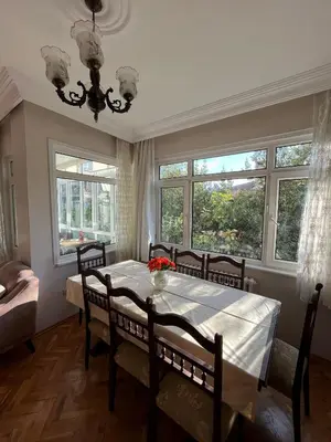 a dining room with a table with chairs and windows at Acıbadem Kadıköy Daire in Istanbul