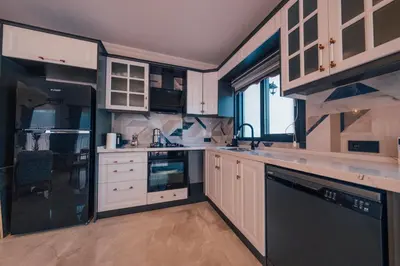 a kitchen with white cabinets and black appliances at Sapanca Göldibi Suit Bungalov in Sakarya