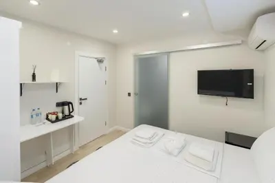 a white room with a bed and a tv on the wall at Casa Florya Suites in Istanbul
