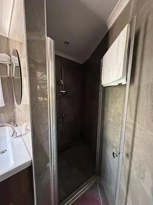 a shower with a glass door next to a sink at Kalimeras Deluxe Hotel in Sapanca