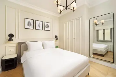 a white bedroom with a bed and a mirror at Vucino Suites in Istanbul