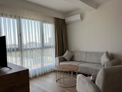 a living room with a couch and a large window at Petra Port Hotel in Tuzla