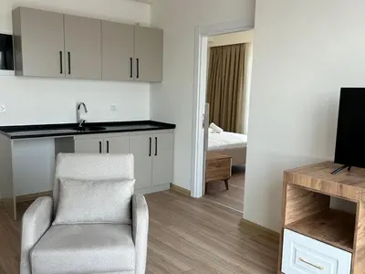 a kitchen and living room with a chair and a television at Petra Port Hotel in Tuzla