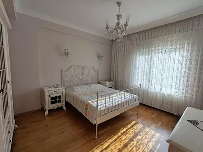 a white bedroom with a bed and a chandelier at Garden Floor Flat in a Beachfront Complex with a Pool in Gümüşyaka