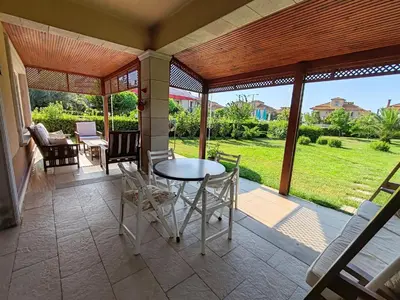 a screened in porch with a table and chairs at Garden Floor Flat in a Beachfront Complex with a Pool in Gümüşyaka