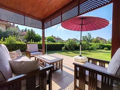 a patio with an umbrella and chairs and a table at Garden Floor Flat in a Beachfront Complex with a Pool in Gümüşyaka