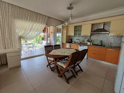 a kitchen with a table and chairs and a kitchen with a view at Garden Floor Flat in a Beachfront Complex with a Pool in Gümüşyaka