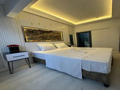 a bedroom with a large white bed and a nightstand at Asıl Kosova Hotel in Istanbul