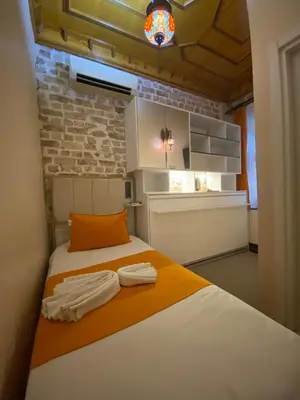 a bedroom with a bed with orange and white sheets at The Astra Hotel in Istanbul