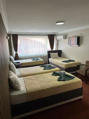 a hotel room with three beds and a window at Hotel Metropol 1 in Istanbul