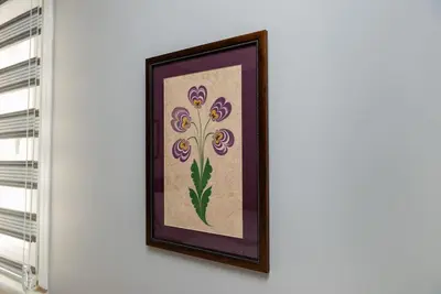 a framed embroidery of purple flowers on a wall at Qbra House in Istanbul