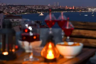 a table with wine glasses and a view of the city at The Maiden Tower From Your Bedroom Romantic View, In Taksim Square in Istanbul
