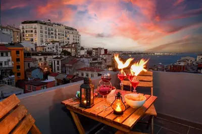 a table with wine glasses on a balcony with a sunset at The Maiden Tower From Your Bedroom Romantic View, In Taksim Square in Istanbul