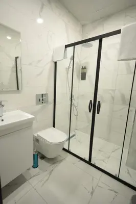 a white bathroom with a shower and a toilet at BZN Airport Hotel in Arnavutköy