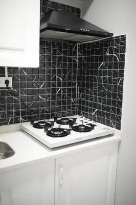 a white stove top in a kitchen with black tiles at Tavra Daltaban in Istanbul