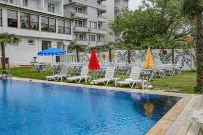 a pool with chairs and umbrellas next to a building at Green Moringa Termal Hotel in Termal