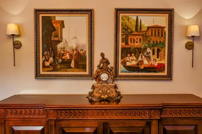 a clock on a wooden cabinet with two pictures on the wall at Boğaz Manzaralı Havuzlu Lüks Villa in Istanbul
