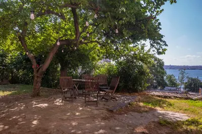 a table and chairs under a tree near the water at Contemporary Waterfront Apt with a Stunning View in Istanbul