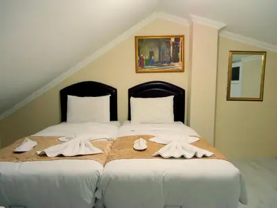 a bedroom with two beds with white sheets and towels at Tolga Hotel in Istanbul