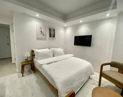 a white bedroom with a bed and a tv on a wall at Nostalgia Apartment in Istanbul