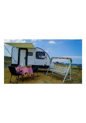 a caravan with a table and chairs in front of it at HUZURLU BİR TATİl - CARAVAN SERENITY in Domalı