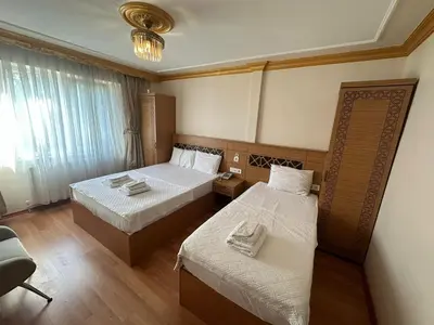 a hotel room with two beds and a chair at Delbab PANSİYON in Istanbul