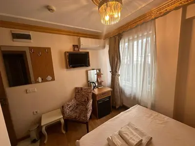 a bedroom with a bed and a chair and a window at Delbab PANSİYON in Istanbul