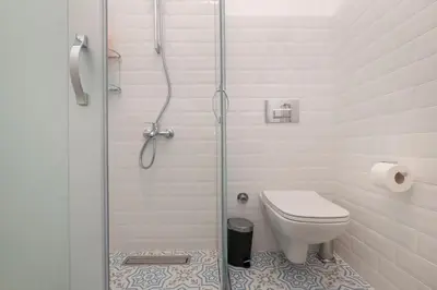 a white bathroom with a shower and a toilet at Hip Waterfront Apt with a Striking View in Istanbul