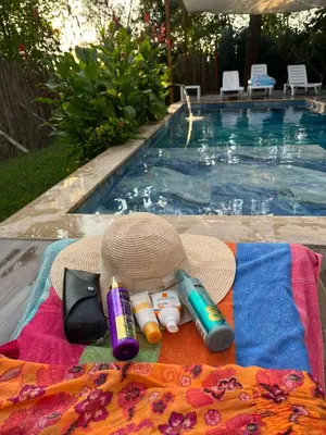 a blanket next to a swimming pool with a hat and lighter at Efe Köy Evi in Sapanca