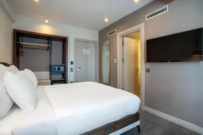 a bedroom with a white bed and a flat screen tv at Smart and Simple Hotel Karakoy in Istanbul
