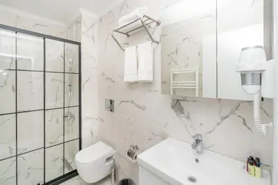 a white bathroom with a toilet and a sink at Guest Suites in Istanbul